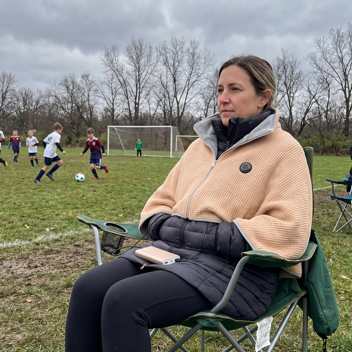 Woman watching a soccer game in the CozyEmber heated shawl