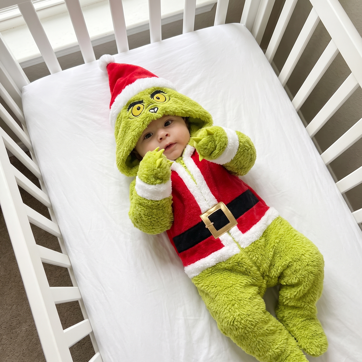 Baby in My Cozy Grump onesie lying in a crib with felt claws out
