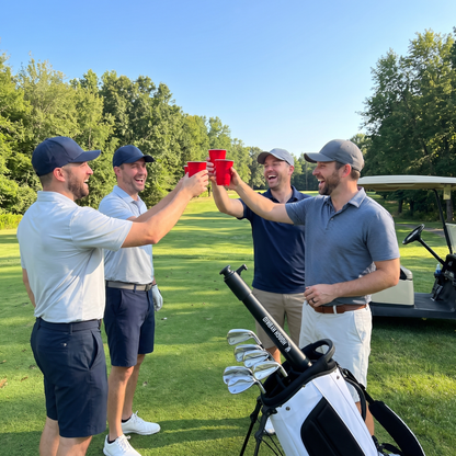 Four golfers cheers with red cups on the tee, Hooch Hybrid standing in the golf bag