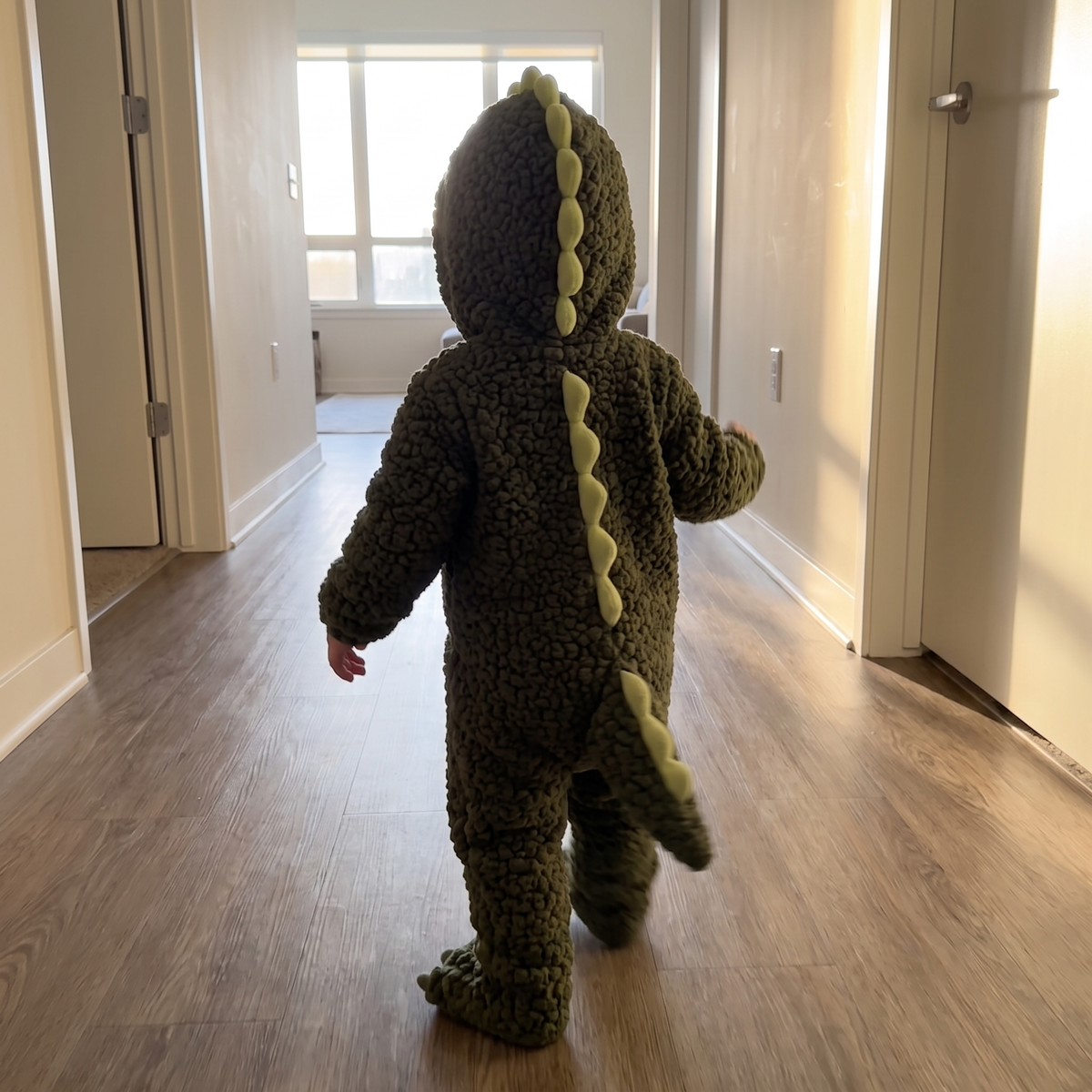 Toddler in the Tiny Dino onesie from behind showing the spikes and tail